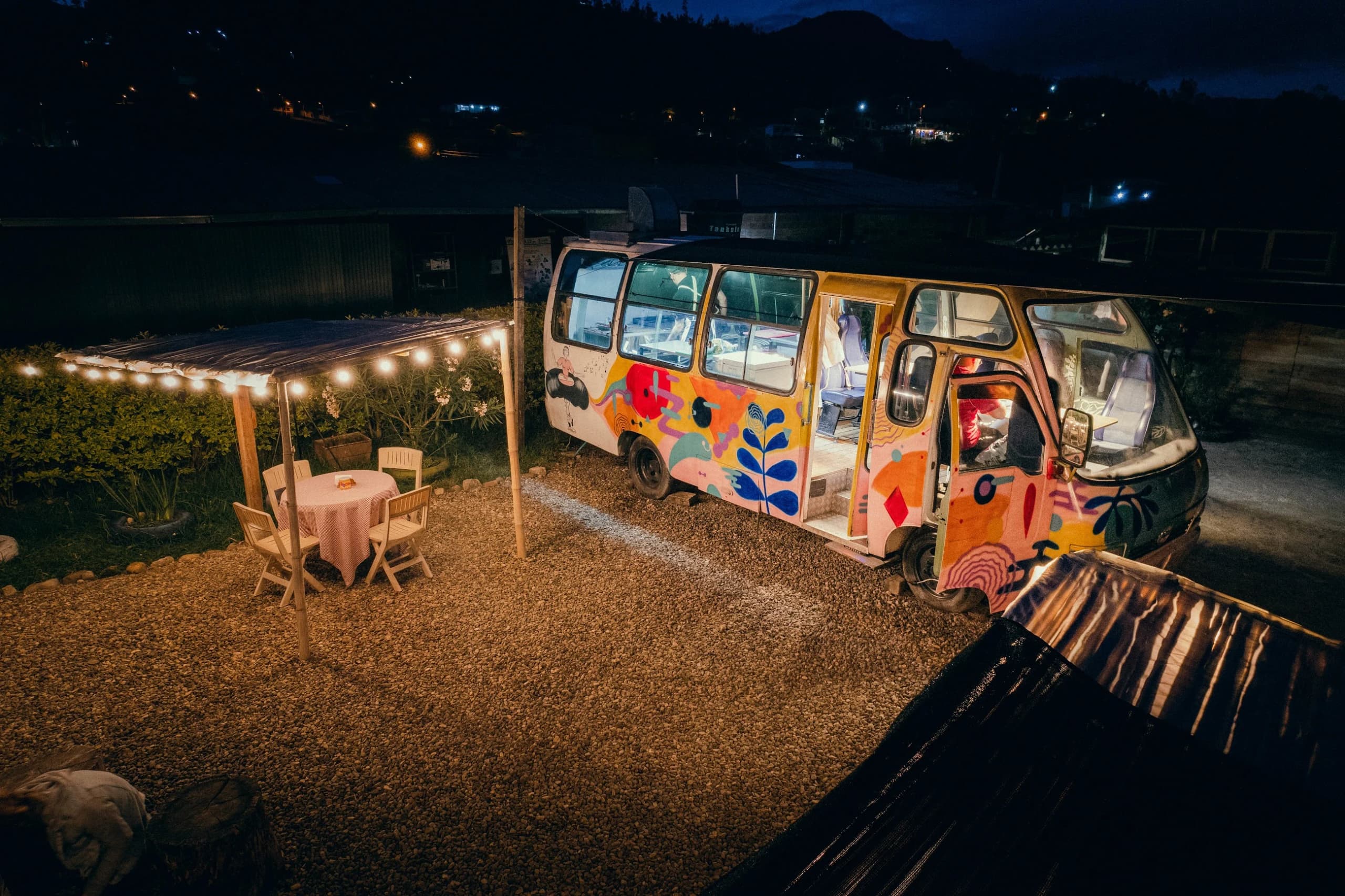 El bus iluminado al anochecer, con las mesas puestas afuera